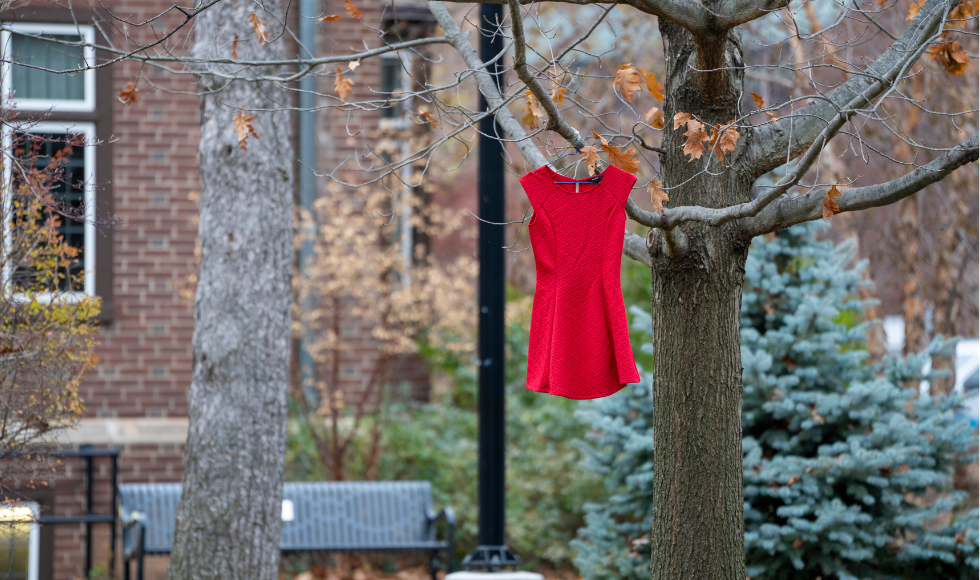 A red dress hanging from a tree on campus..
