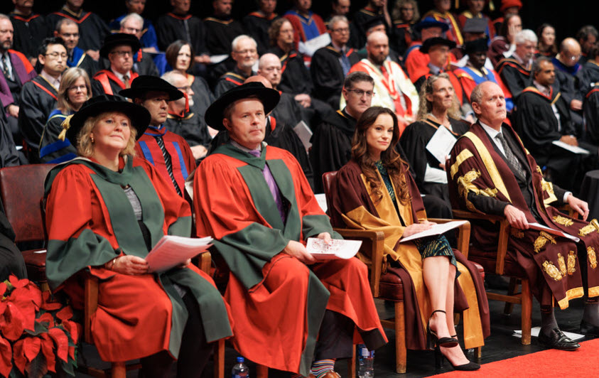 A crowd of people in convocation regalia seated on a stage