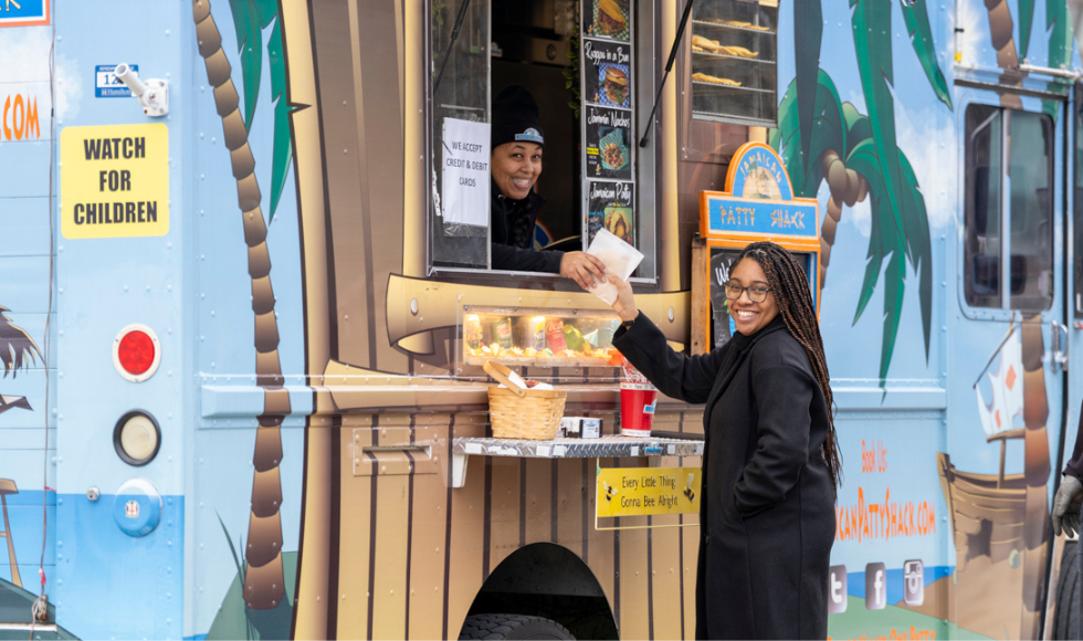 A woman buys a patty from the Jamaican Patty Shack food truck at BHM at Mac launch event 2024
