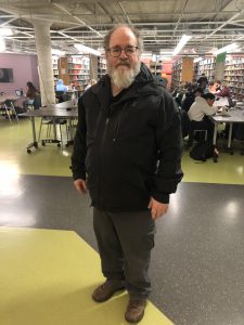 Image of Stewart Patch standing in Thode Library smiling for a picture