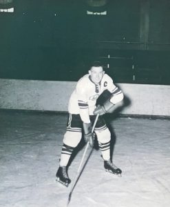 A black and white photo of Ross Mason in action on the ice, wearing a jersey with a 'C' on it, indicating he is the team captain.