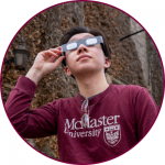 A McMaster student wearing eclipse glasses while looking up at the sky