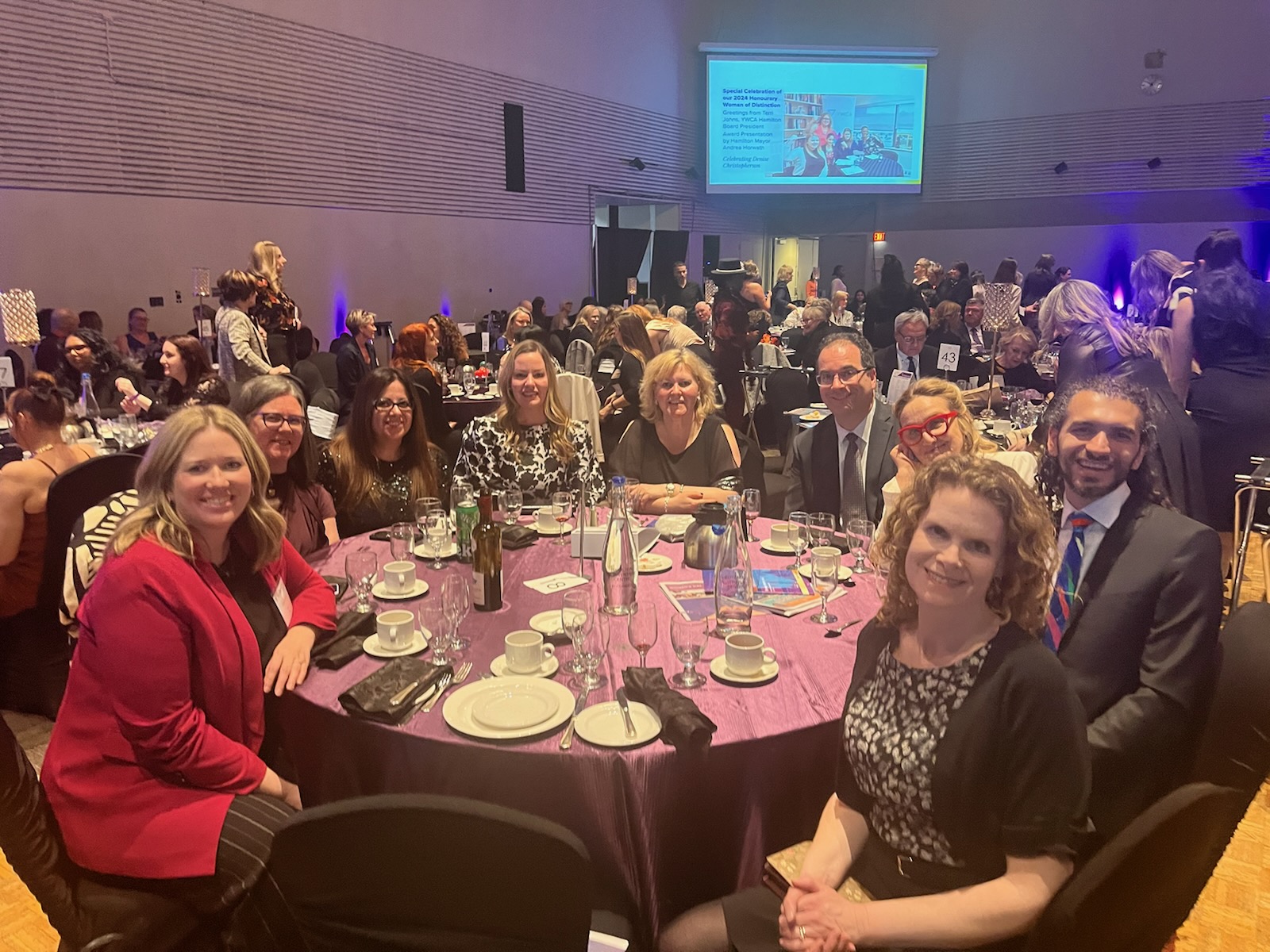 A group of smiling people sitting around a round table at an event.