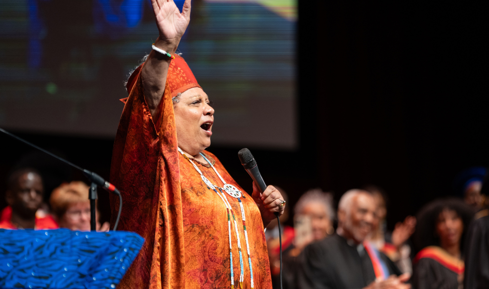 Jackie Richardson stretches her hand out as she hits a high note on stage at the 2024 Black Excellence Graduation Celebration.