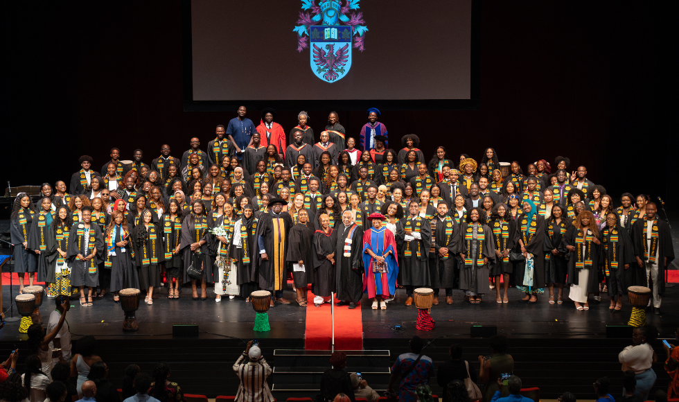 All the graduating students and attending faculty members pose for a huge group picture on stage at the 2024 Black Excellence Graduation Celebration.