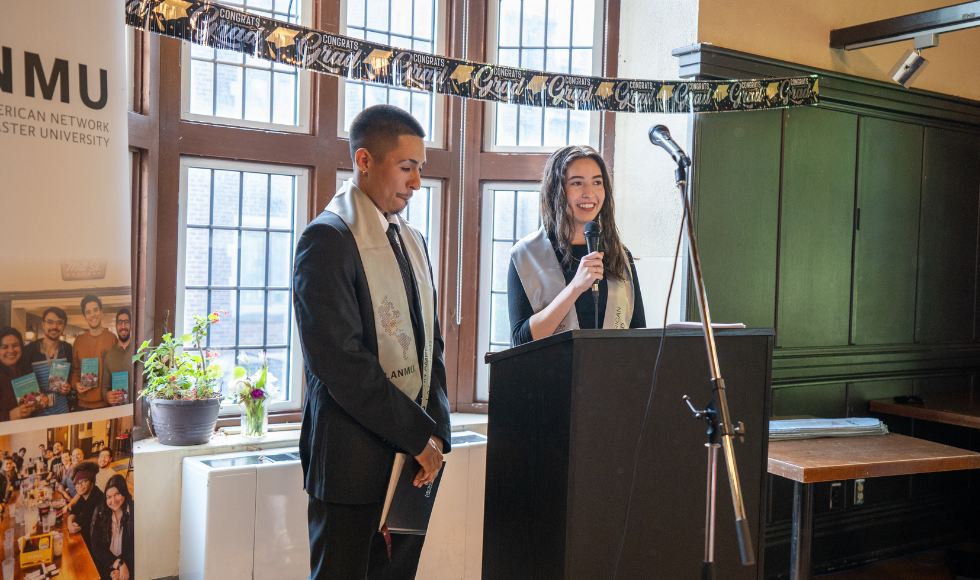 One woman speaking into a microphone at a podium. There is a man standing beside her.