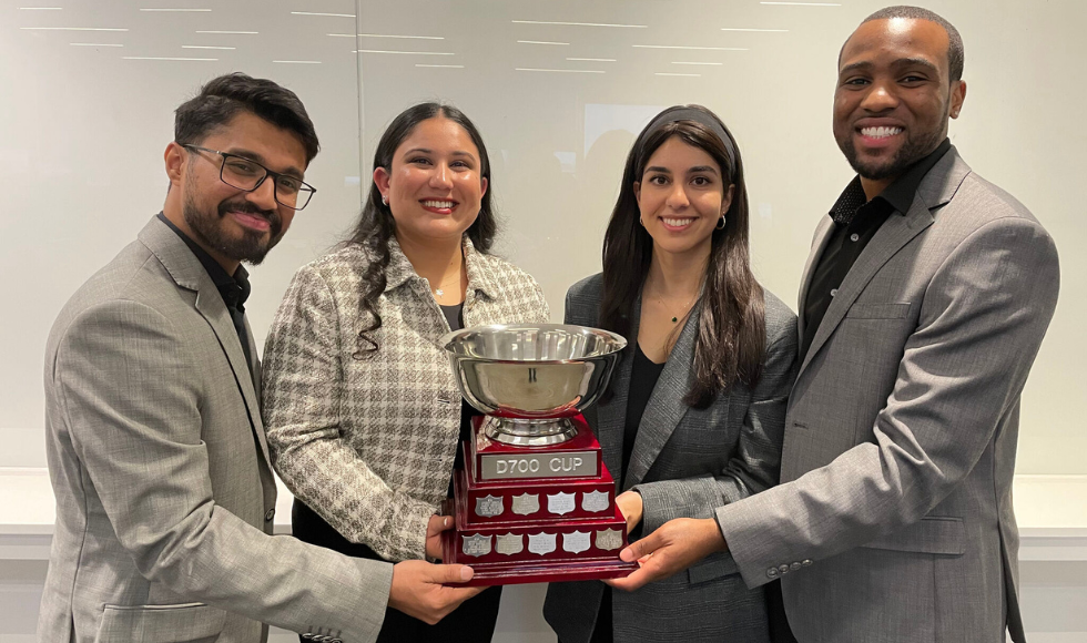 Four people holding up a large trophy 