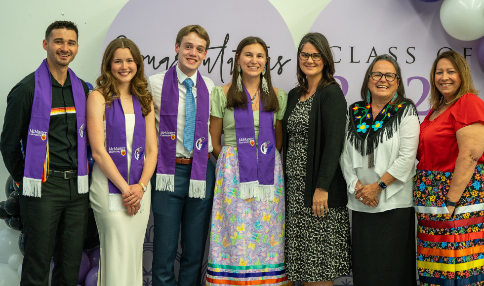Seven people, four of whom are wearing purple stoles, pose for a photo. 