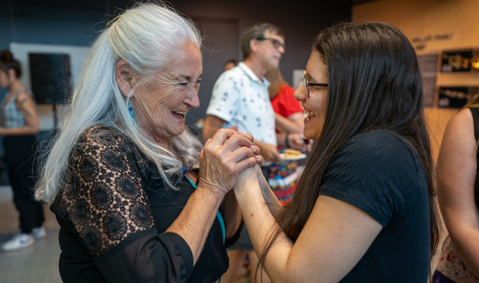 Kathy Knott and a graduating student clasp hands and smile at the 2024 Indigenous Graduation Celebration.