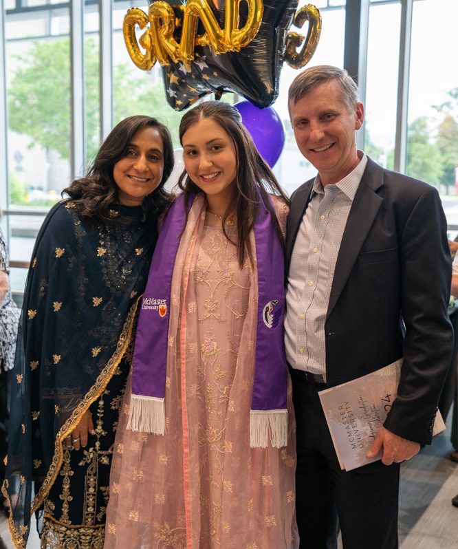 A smiling student poses with her parents