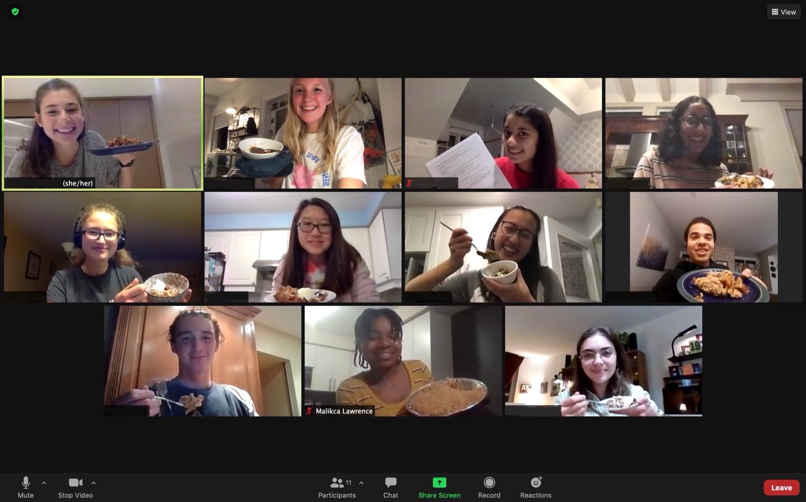 A screenshot of a Zoom meeting featuring smiling students. Some of them are holding up bowls of apple crumble. 