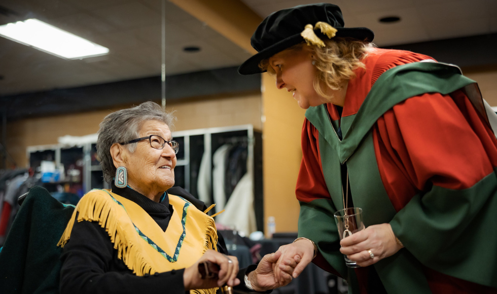 Bertha Skye in conversation with McMaster Provost Susan Tighe. Tighe is wearing convocation regalia. 