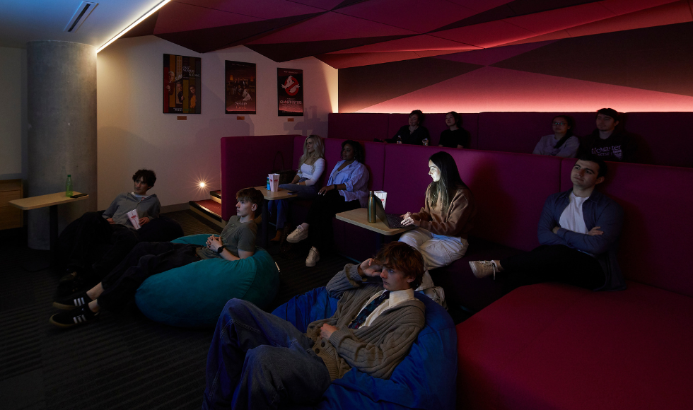 A group of people seated in a dark theatre room.