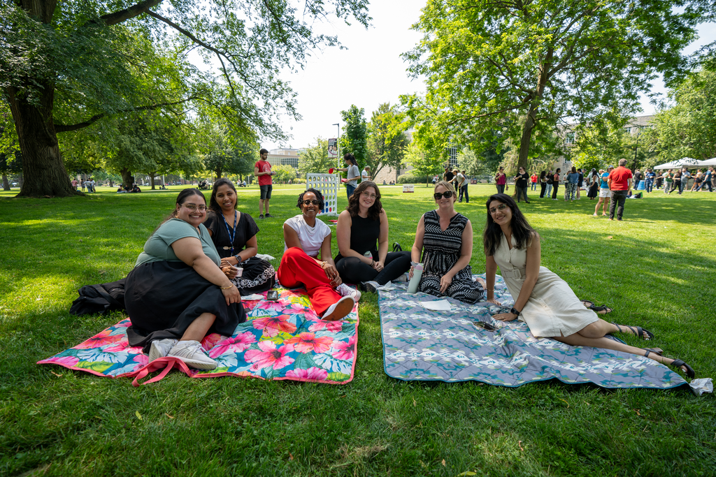 Staff and faculty members take a break on picnic blankets in the shade on BSB field