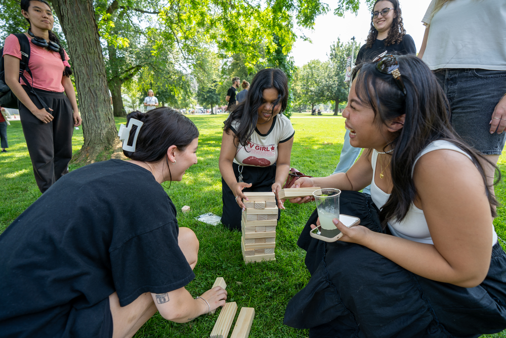 Students and staff kneel down to play Jenga on BSB field during the ice cream social.