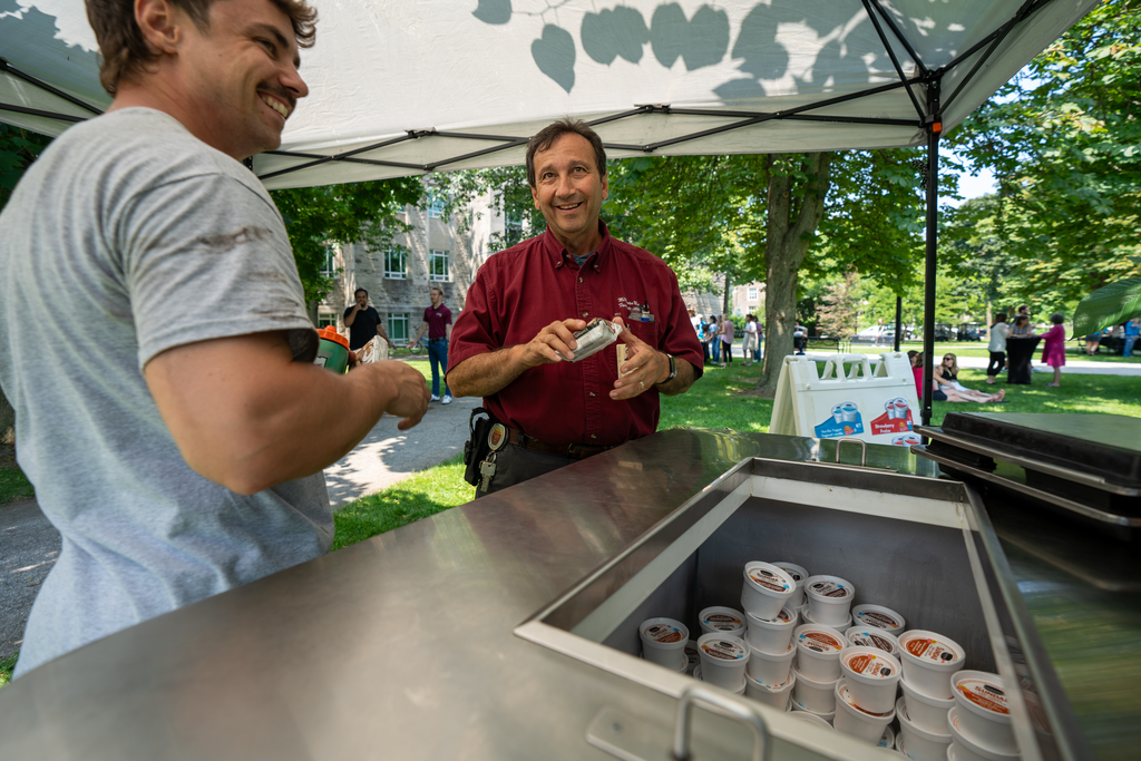 Two people standing at a metal ice cream cart.