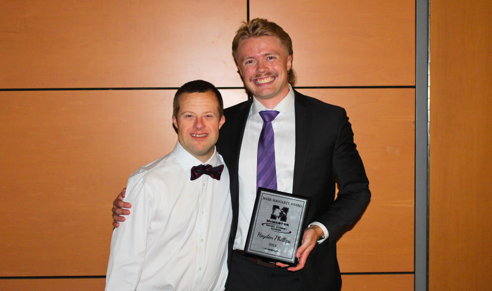 Mark Haggarty and another person smiling and looking at the camera. The other person is holding a plaque that reads, 'The Mark Haggarty Spirit Award.'