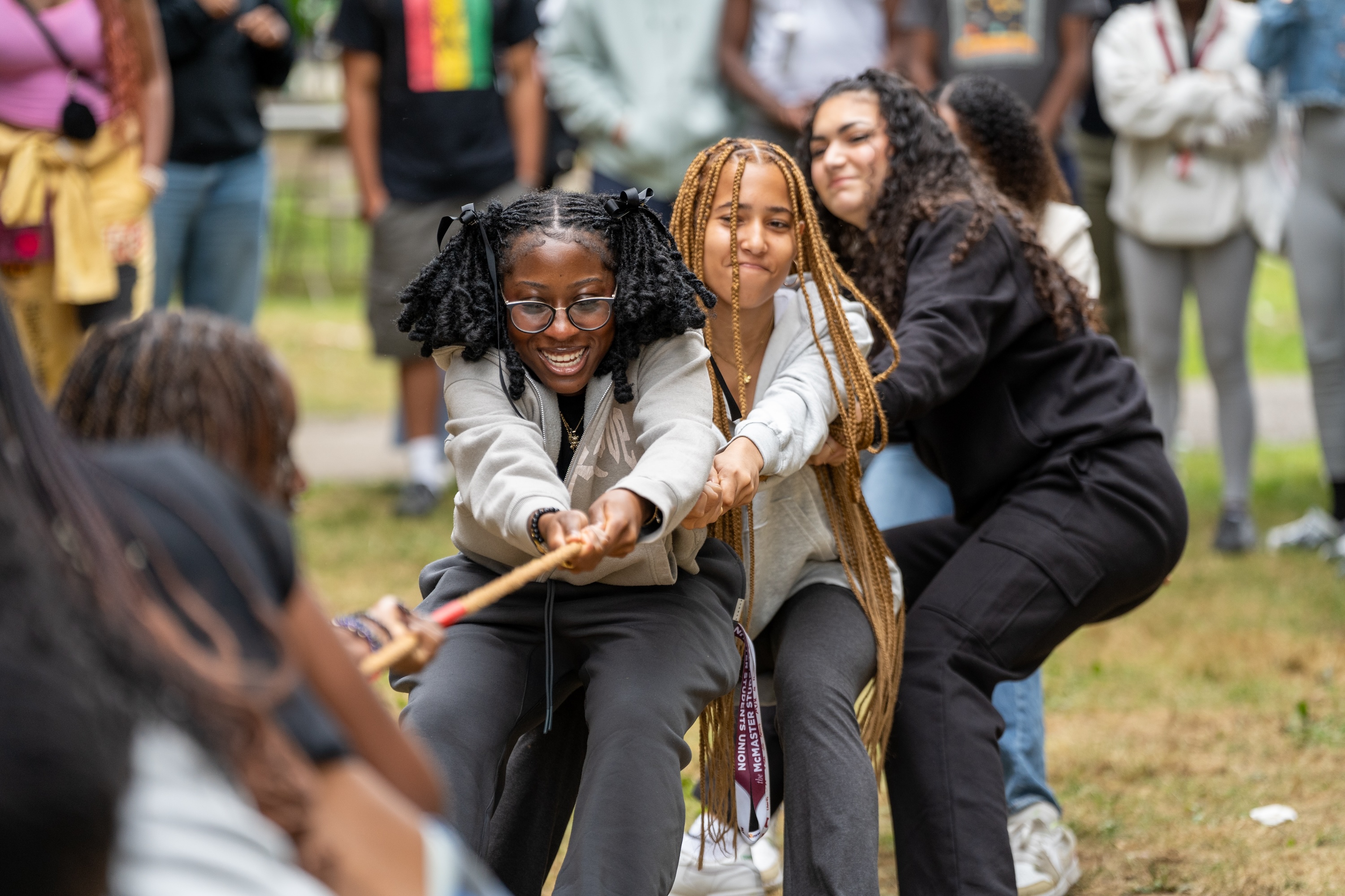 A group of students pulls hard in a tug of war.