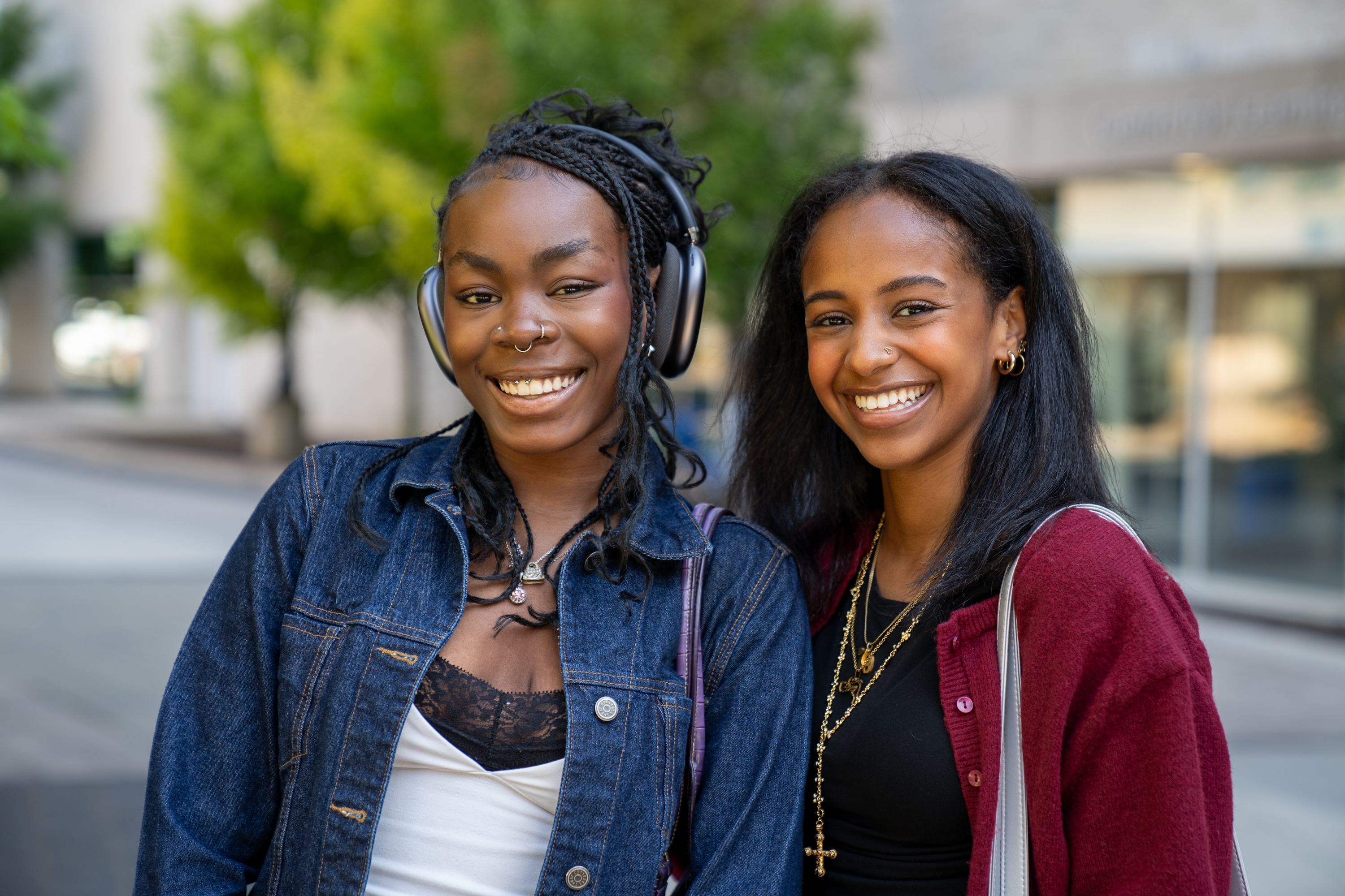 Two smiling young women standing together outside a building on campus