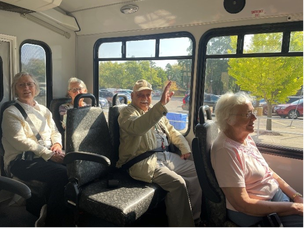 A handful of older adults seated inside a beu 