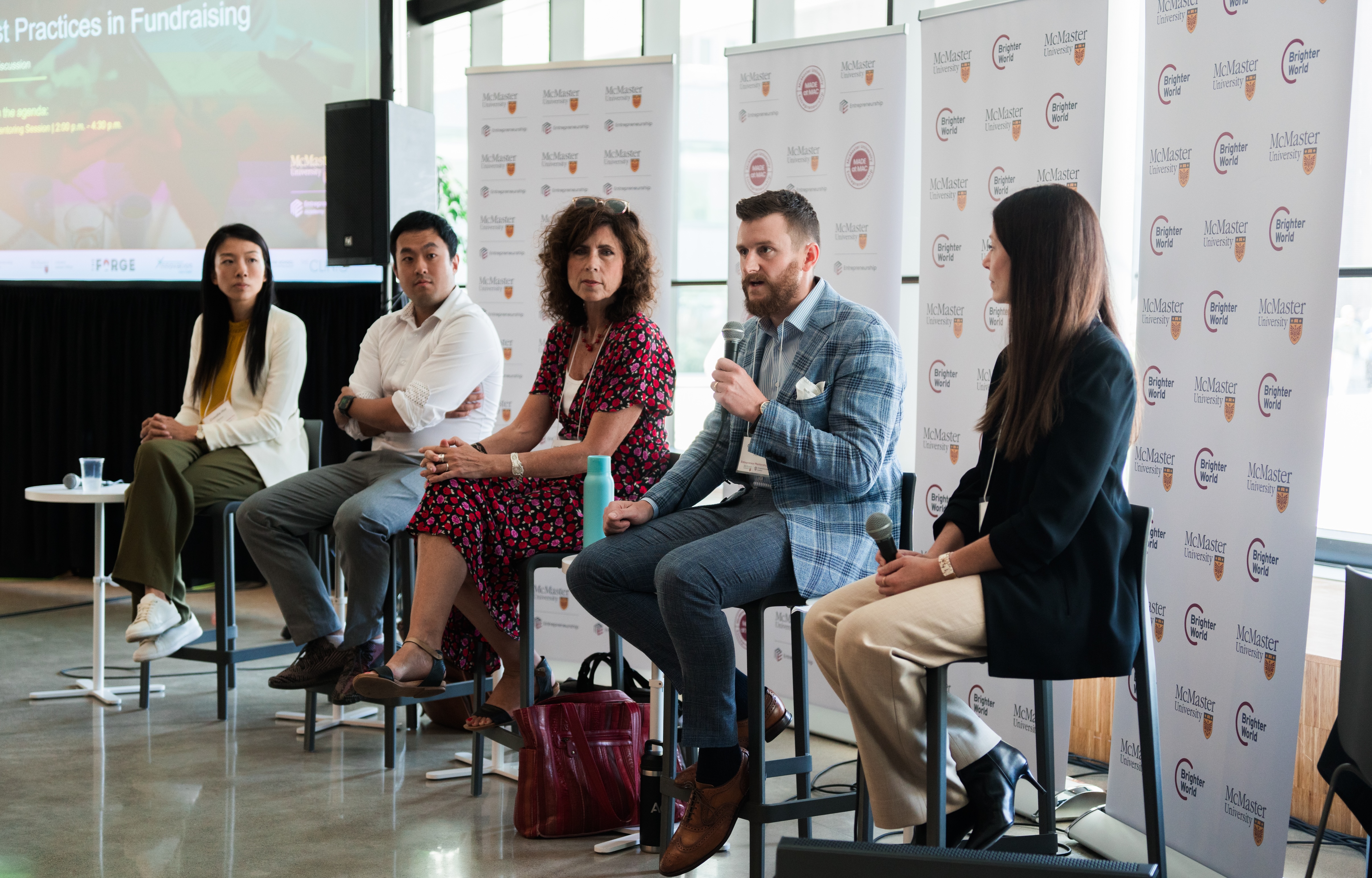 A row of panelists seated against a backdrop of McMaster panels.