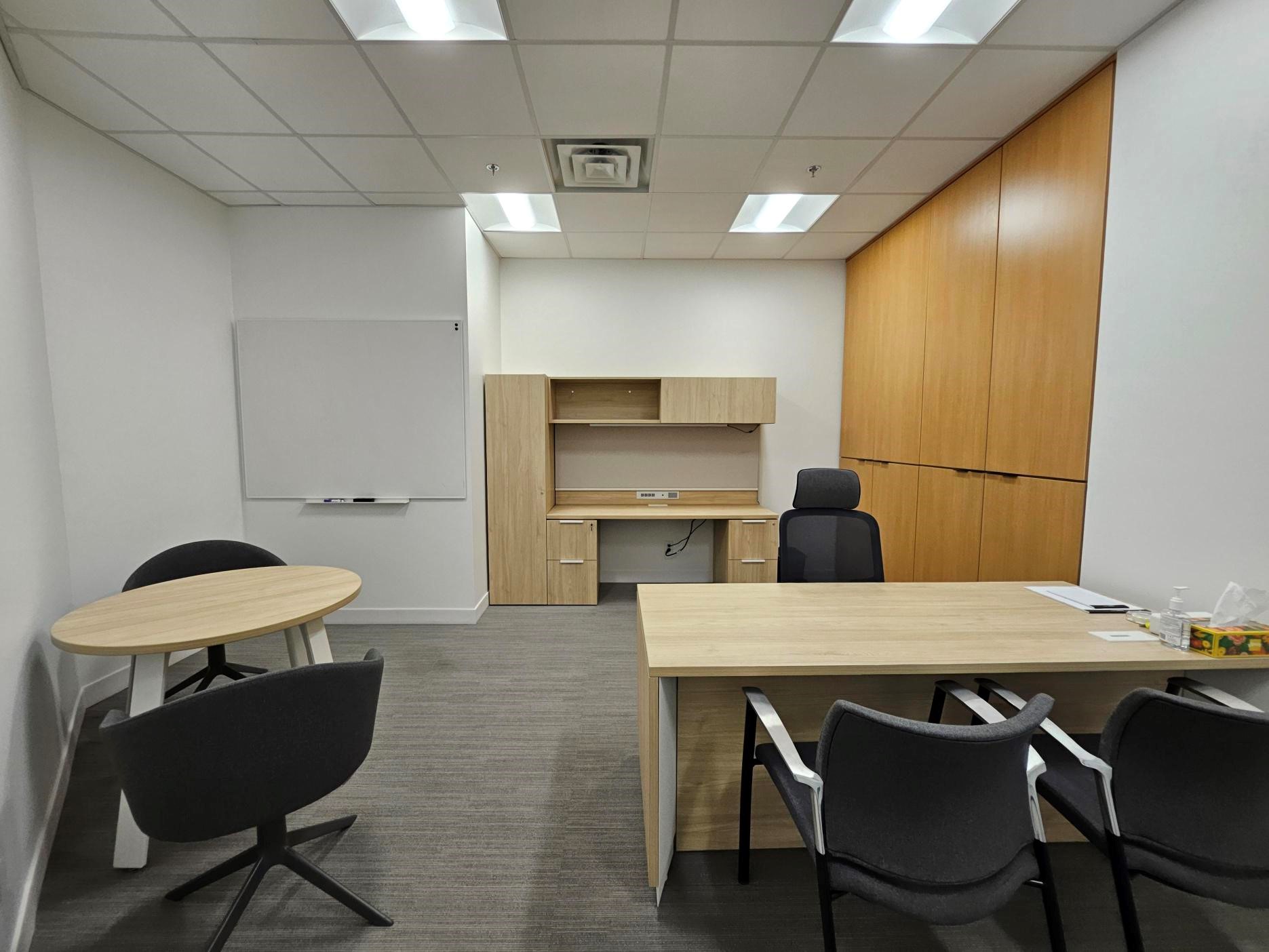 An office with two desks, a small round table and a whiteboard. 