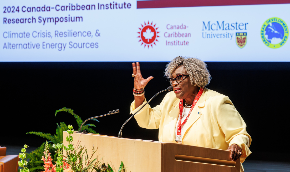 Elizabeth Thompson gestures with her hand while speaking at a podium on stage