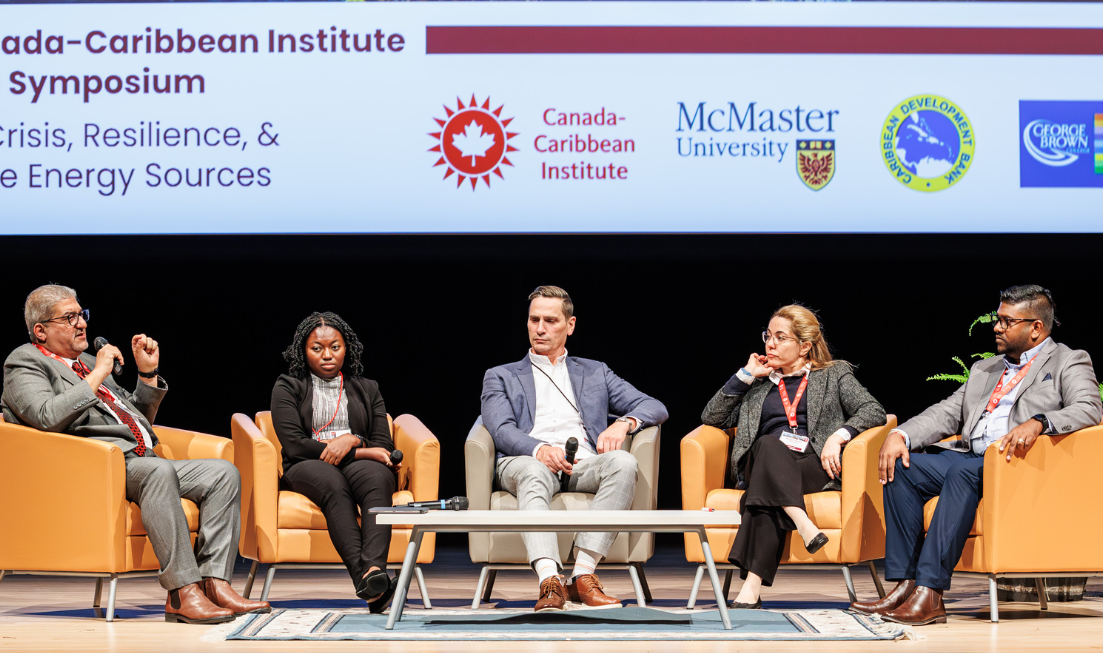 five panellists sit in armchairs on stage for a panel discussion.