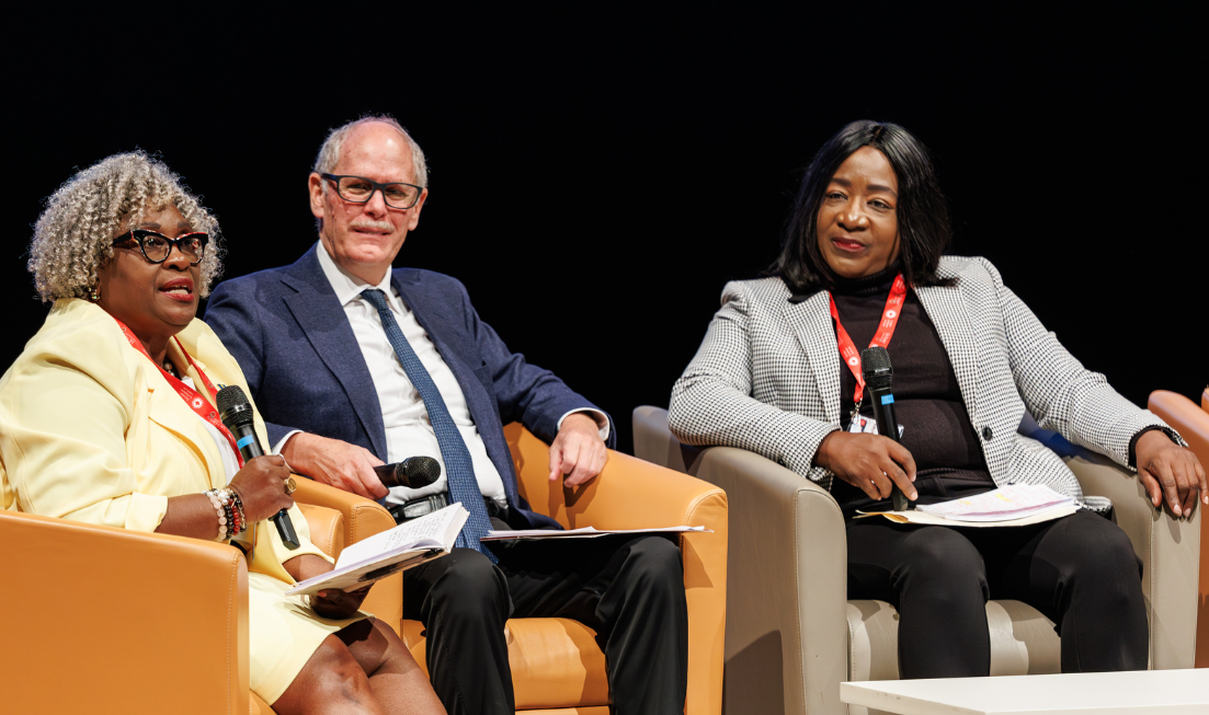 Elizabeth Thompson, David Farrar and Julie Lashell Adderley sit on chairs on stage holding mics during a panel discussion.