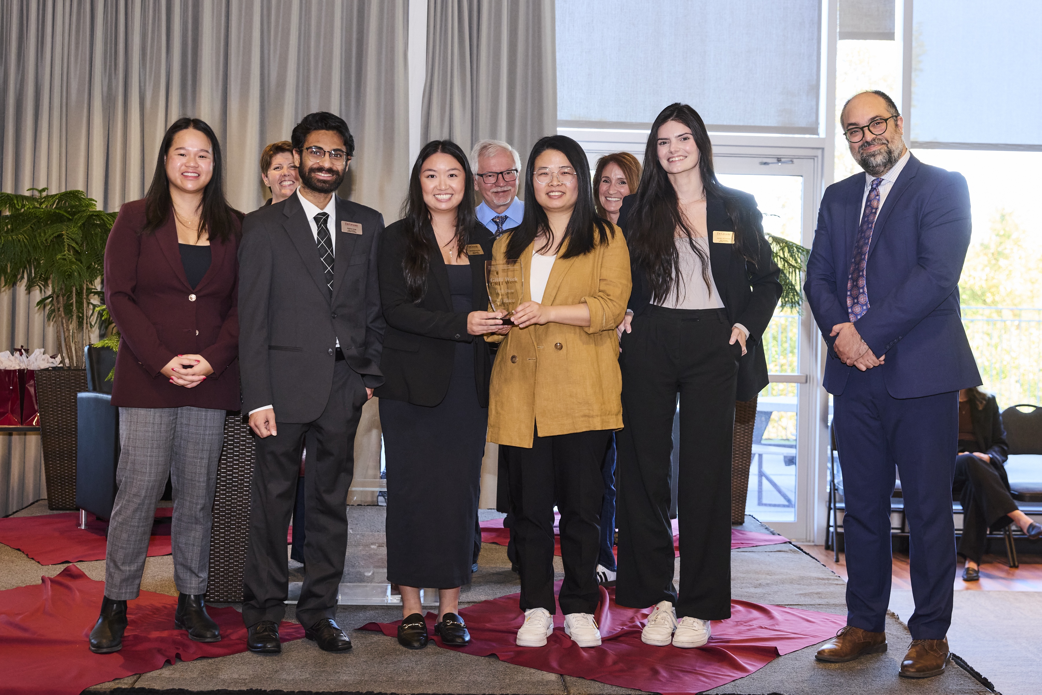 A group of students and judges stand on stage with a trophy.