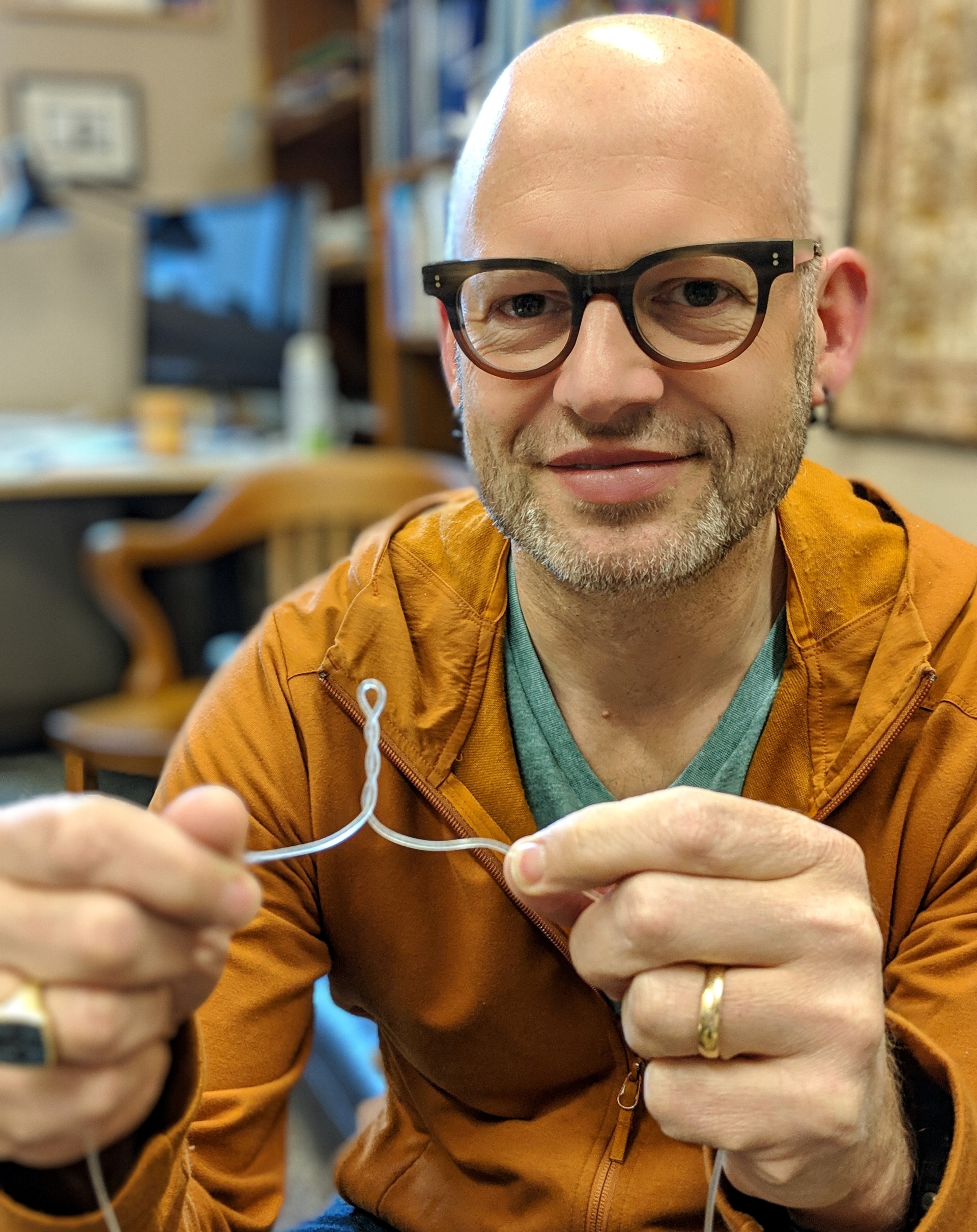 Kari Dalnoki-Veress looking directly at the camera while holding up a plastic wire 