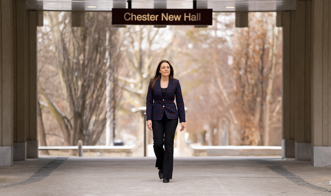 Kristina Llewellyn walks under the sign for Chester New Hall in front of Edwards Arch.