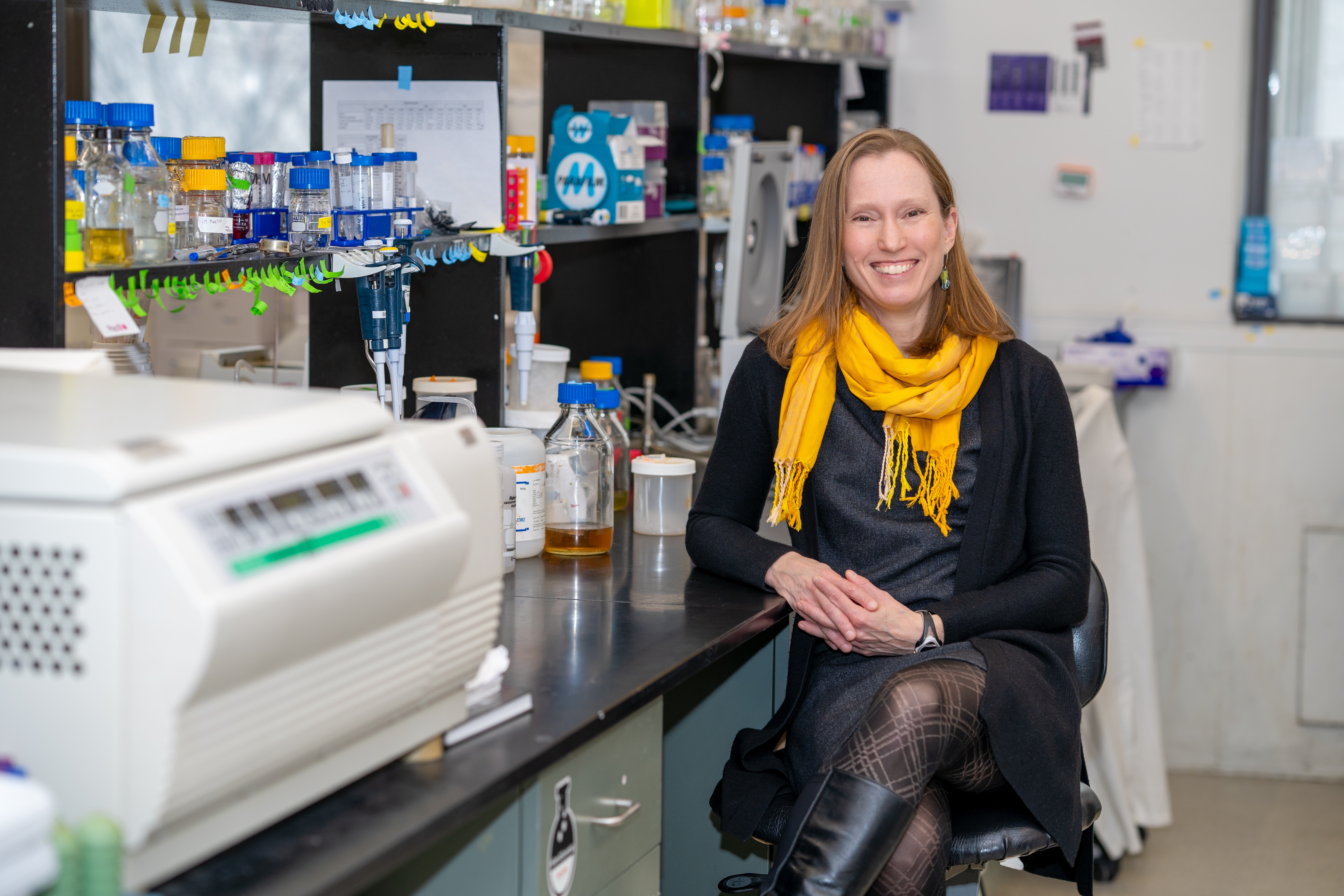 Marie Elliot sits in a lab, surrounded by scientific gear and apparatus.