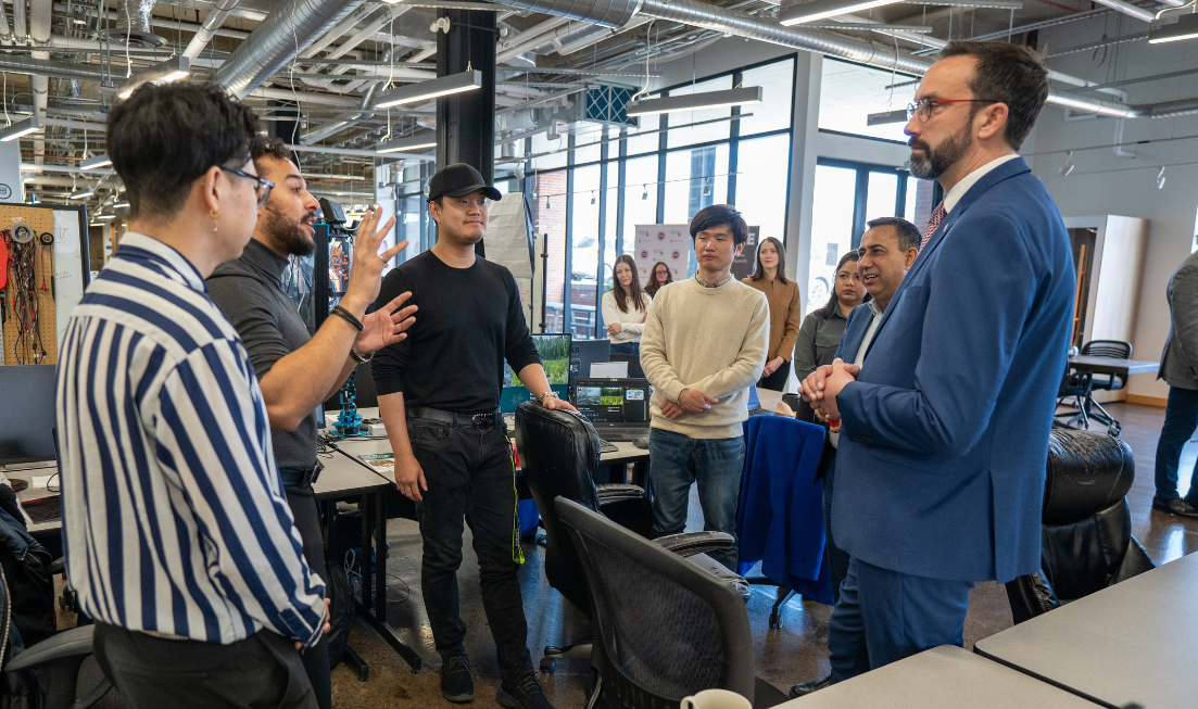 A group of people chats animatedly with a person in a blue suit.