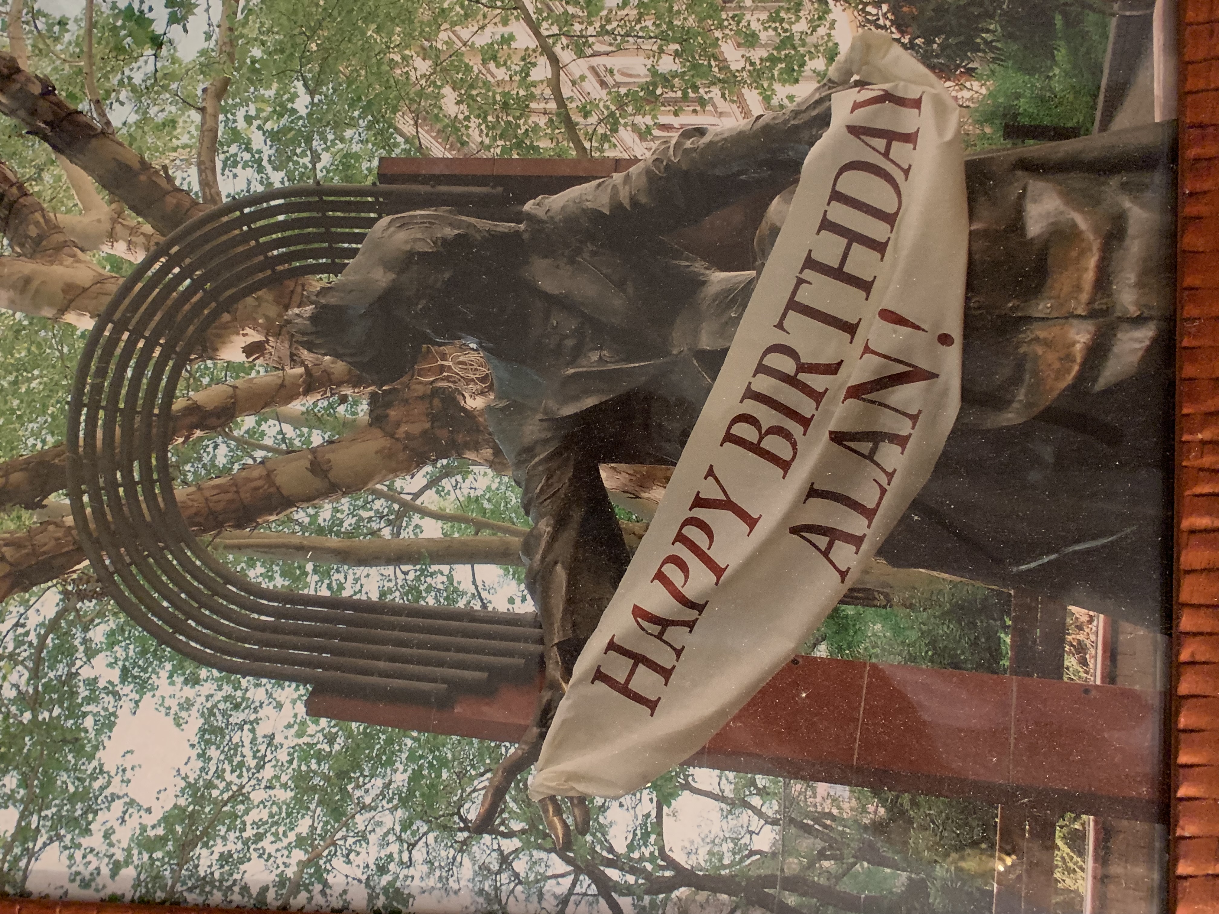 A statue holds a banner that reads 'Happy Birthday Alan!'