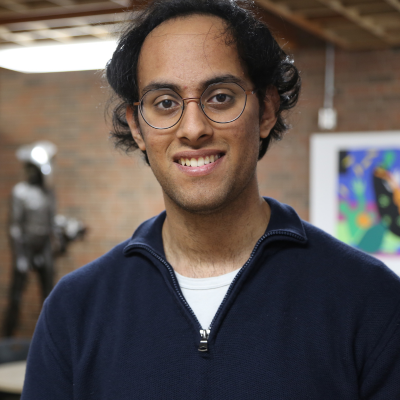 A headshot of a man in glasses and a blue sweater. 