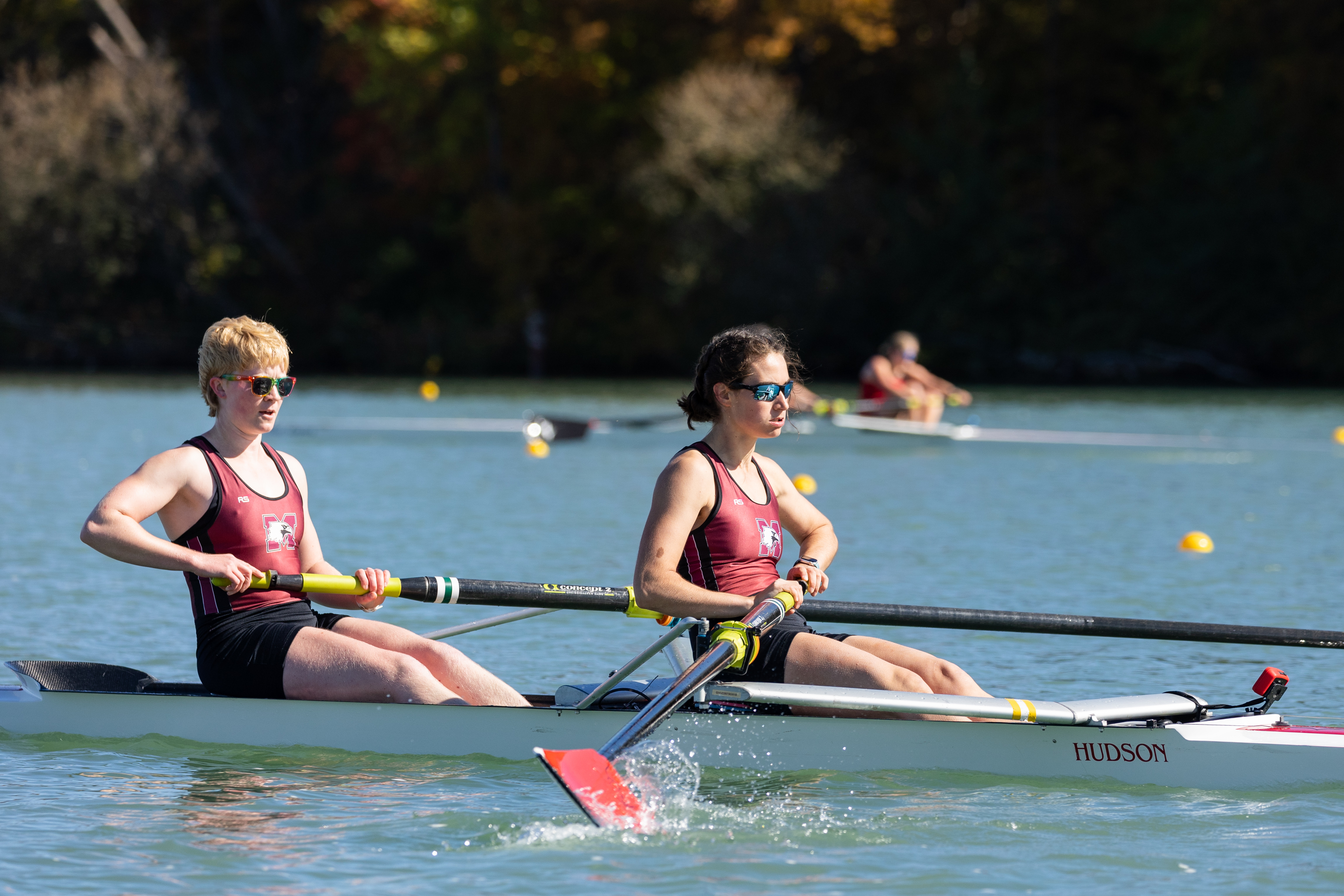 Two women row on the water.