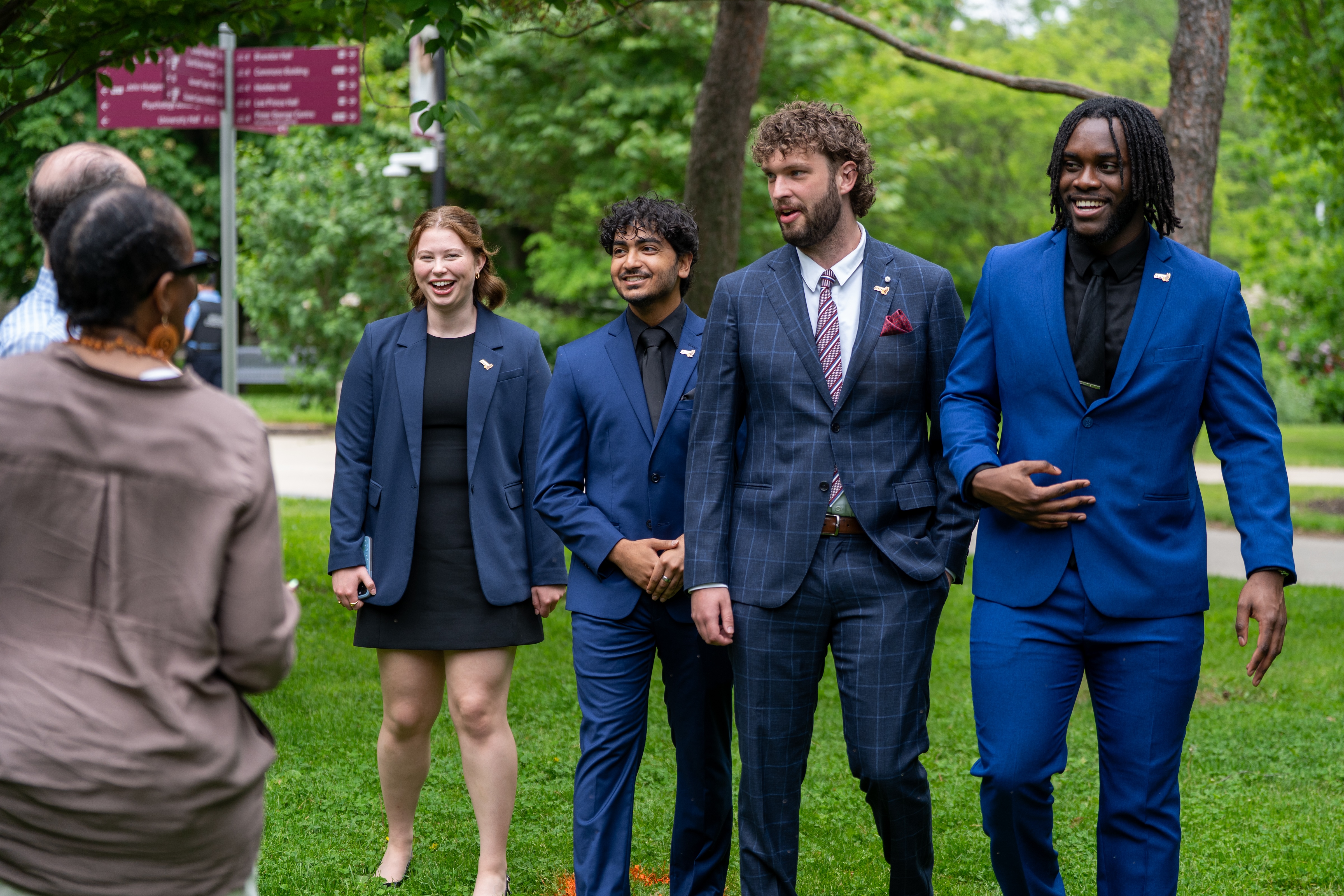 Four student leaders in blue formalwear outdoors on campus