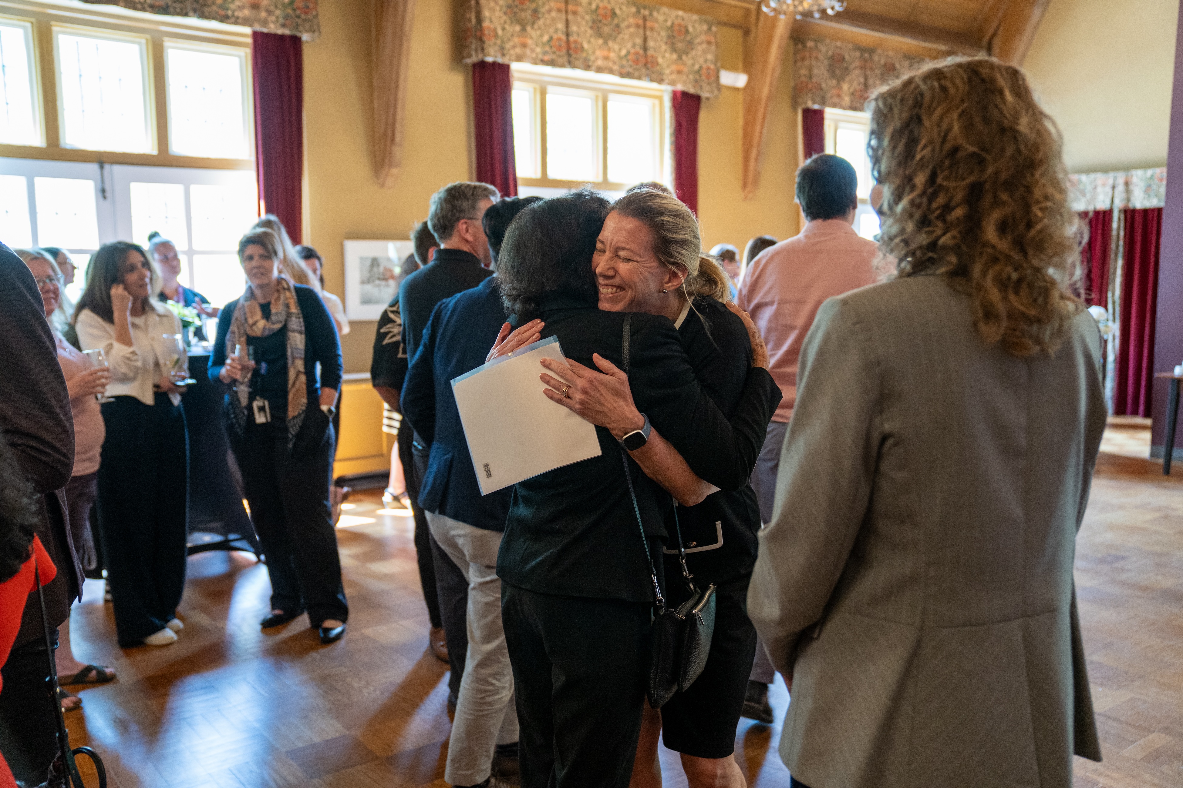 Smiling Maureen MacDonald hugs someone in Alumni Memorial Hall