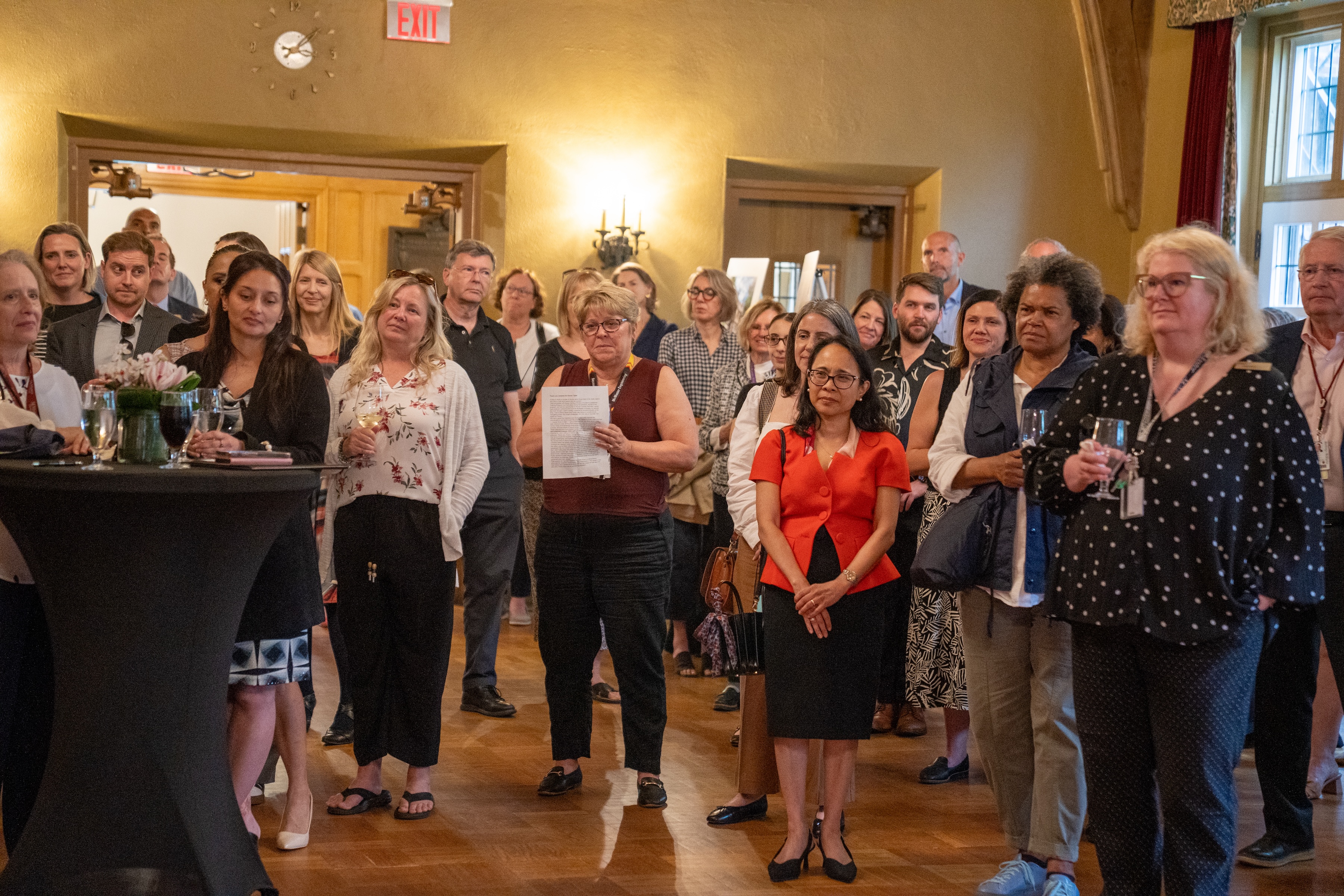 A group of people face a speaker during a gathering in Alumni Memorial Hall