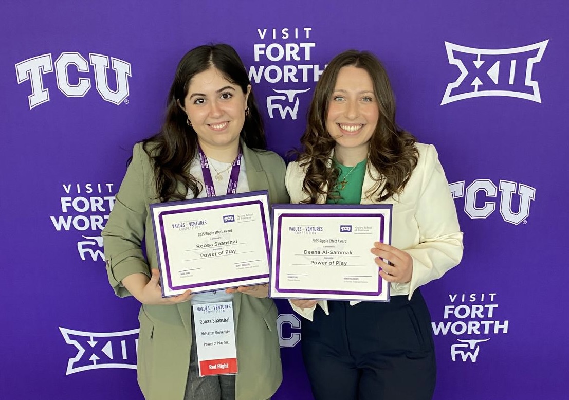 Two women in professional wear stand against a purple backdrop, each holding up a certificate.