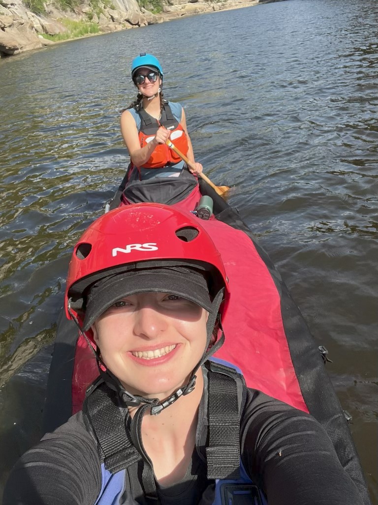 Two women smile in a canoe.