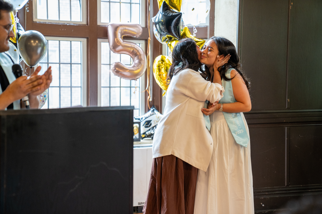 Two women embrace on a stage.