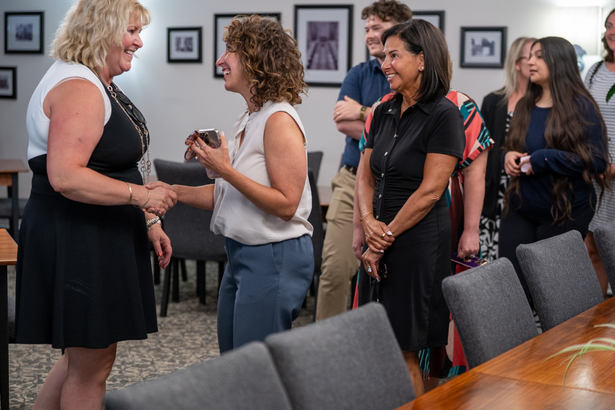 Susan Tighe and McMaster staff and faculty members smile and chat at a gathering.