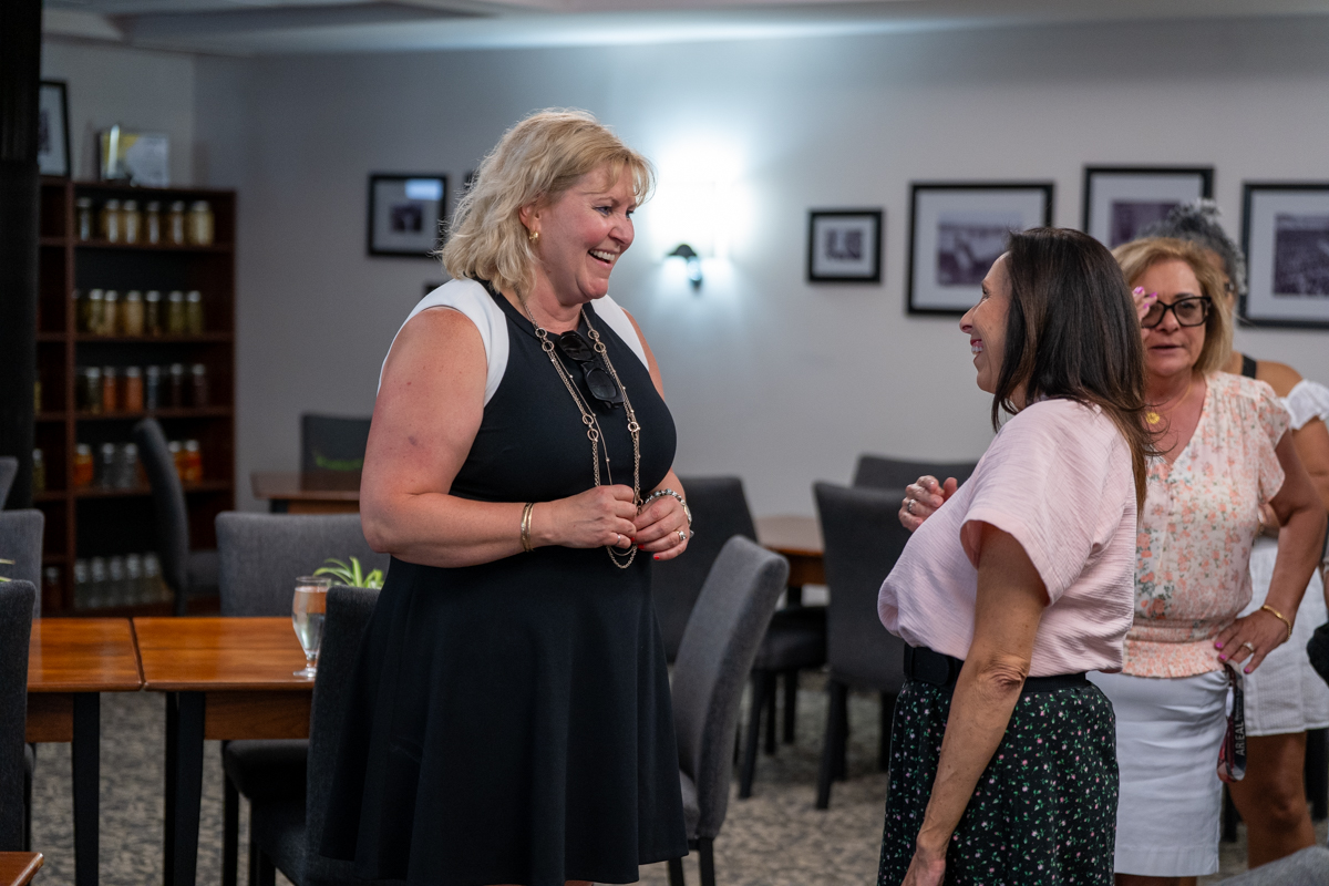 Susan Tighe and McMaster staff members smile and chat at a gathering indoors.