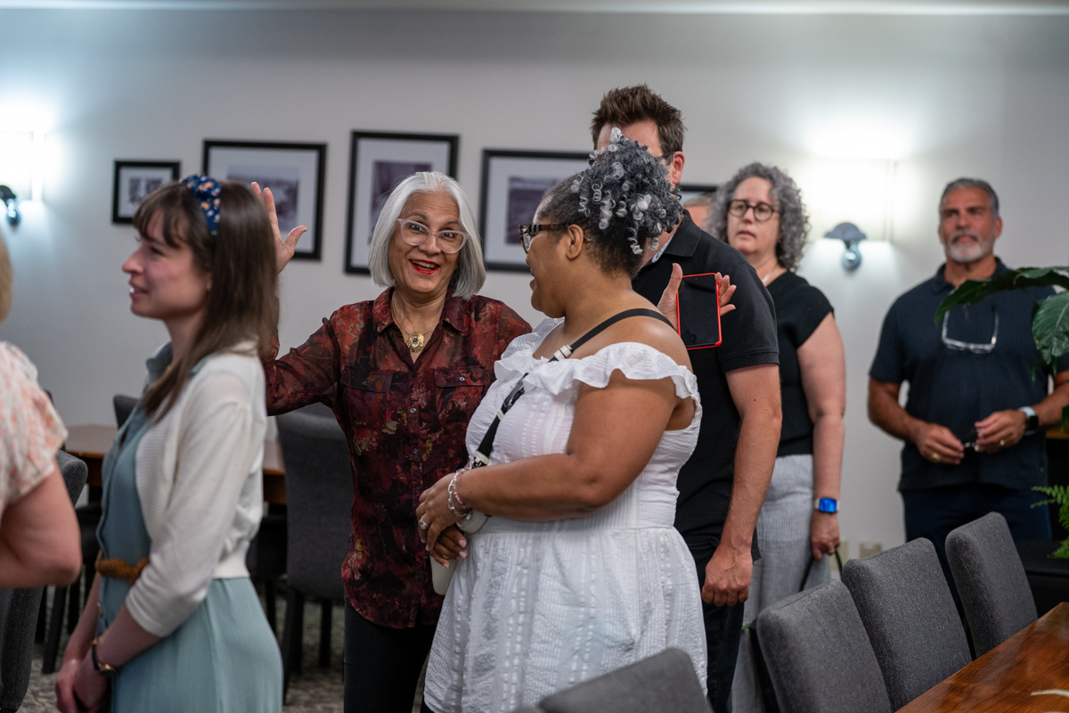 staff and faculty members chat at a gathering indoors.