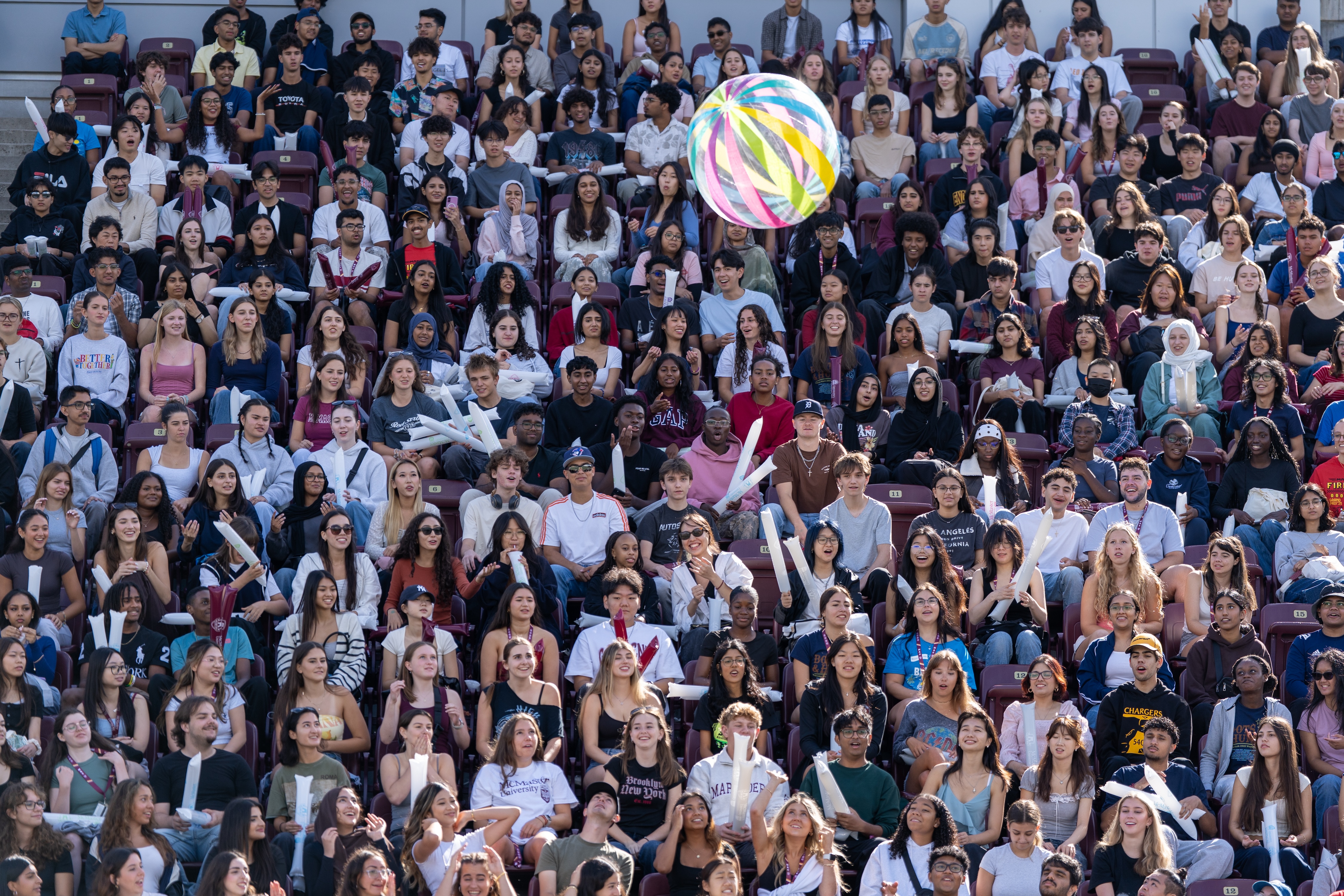 A big beach ball is in midair above stands full of students at the stadium during welcome week 2025