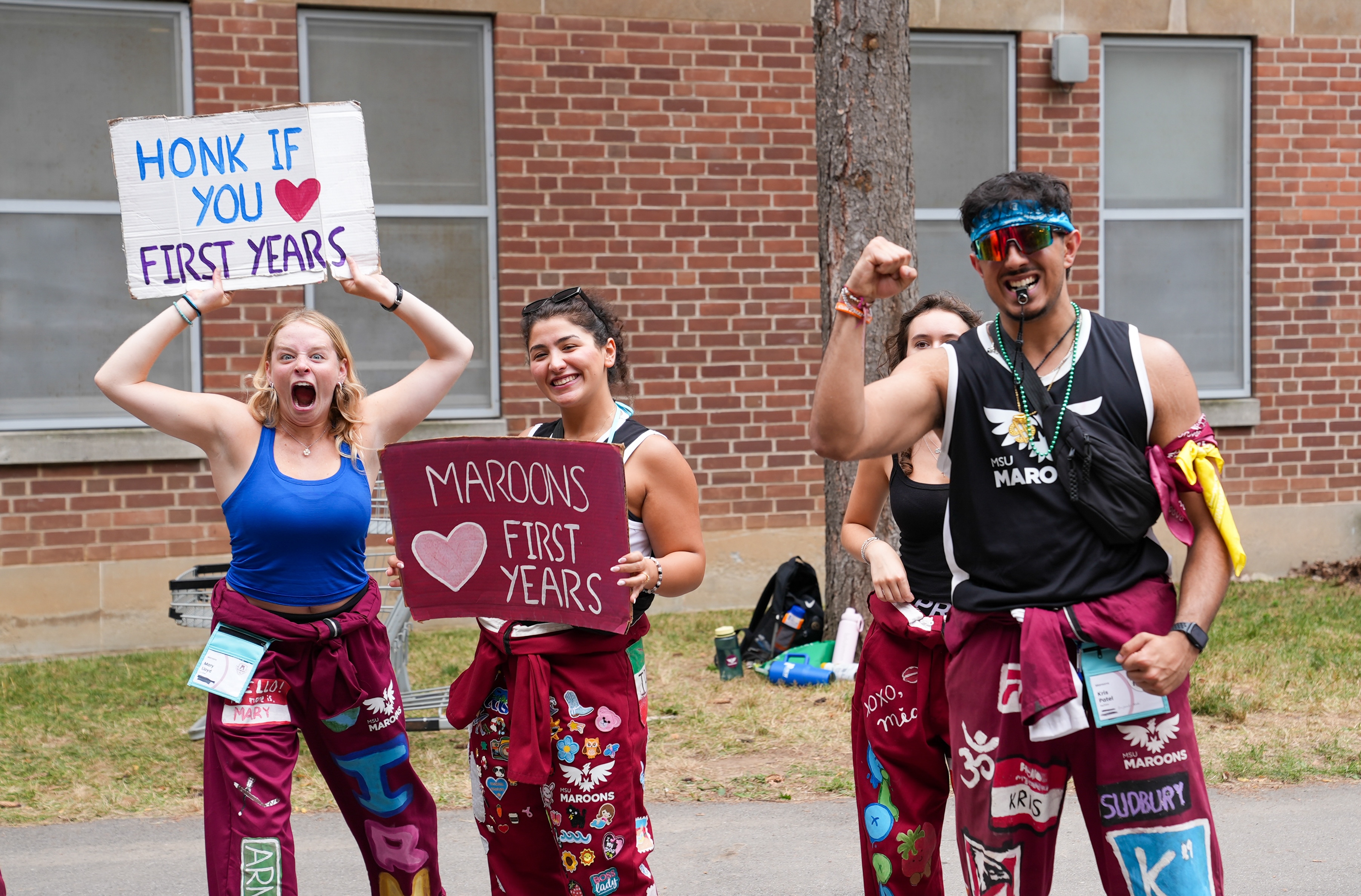 Welcome Week reps cheer and hold up signs welcoming first-years at Move-In weekend