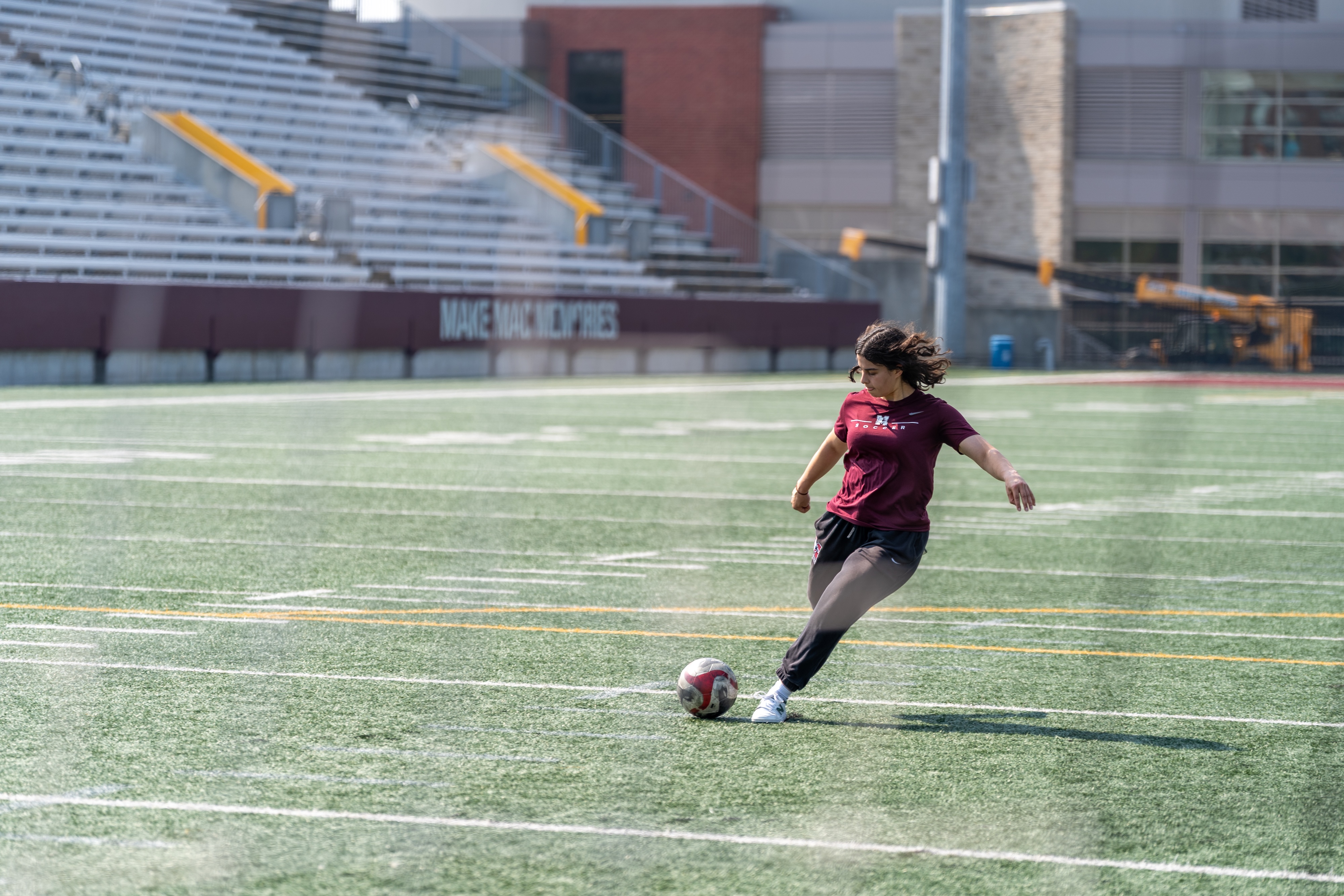 A woman runs and prepares to kick a soccer ball on a field.