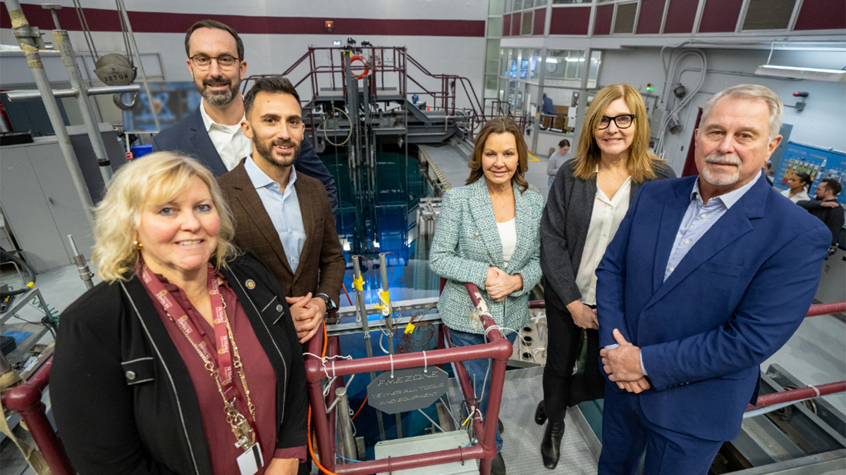 Six people at a nuclear reactor, smiling to camera.